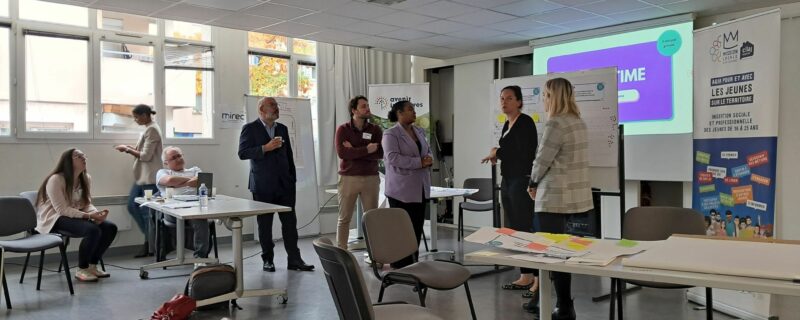 GEYVO recrutement en temps partagé au MIREC sur le thème « Tutorat, mentorat et parrainage : des solutions concrètes au service du retour à l’emploi ». Gens dans une salle avec table et écran de projection.